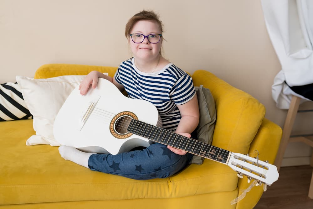 Young teenage girl with Down syndrome learning to play the guitar