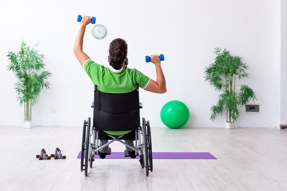 Young man in wheel chair doing exercises indoors