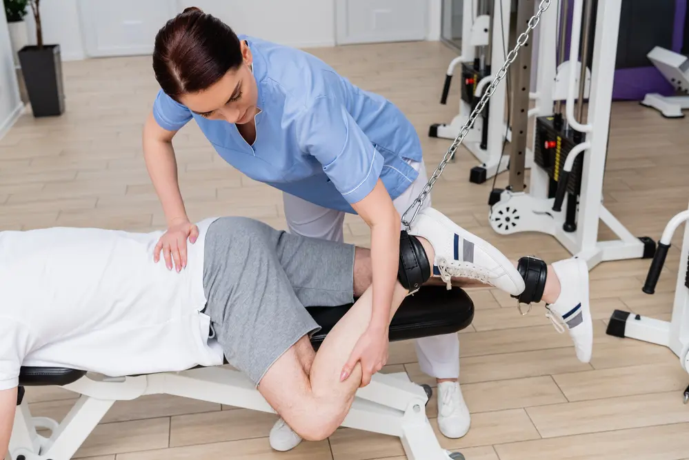 Brunette physiotherapist stretching leg of man