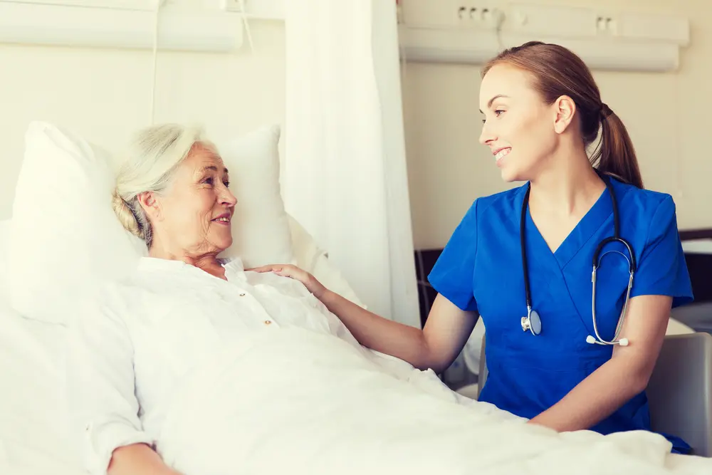 Doctor or nurse visiting senior woman at hospital