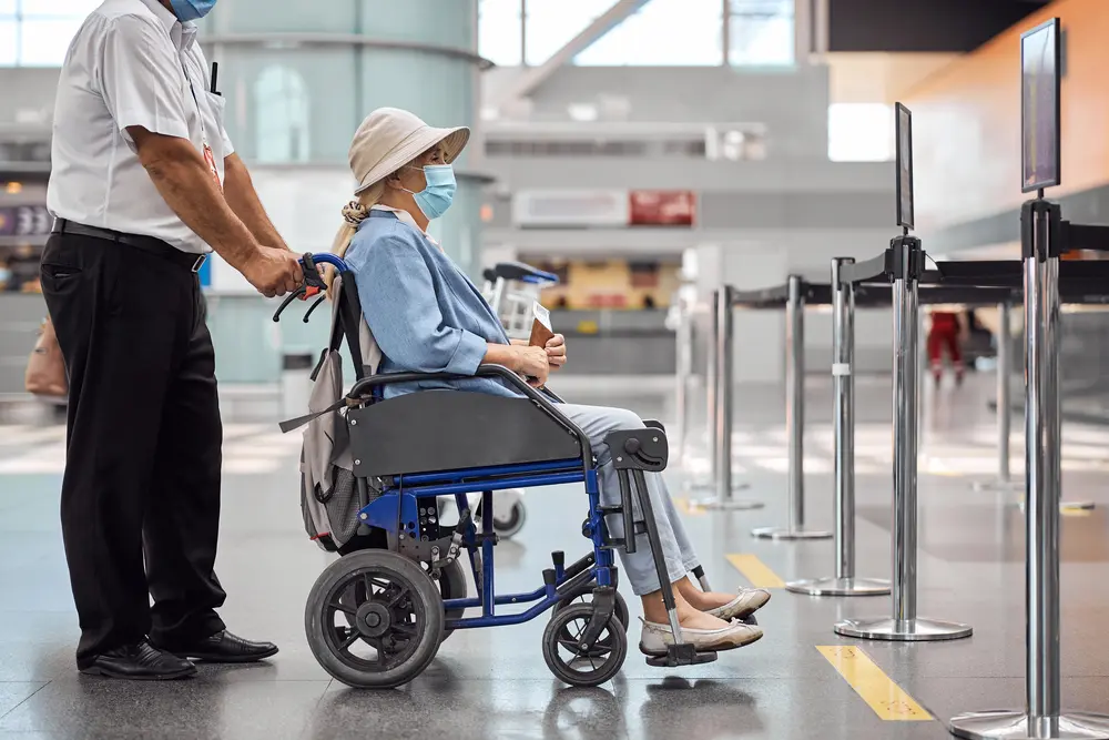 Airport worker rolling a wheelchair with a senior woman