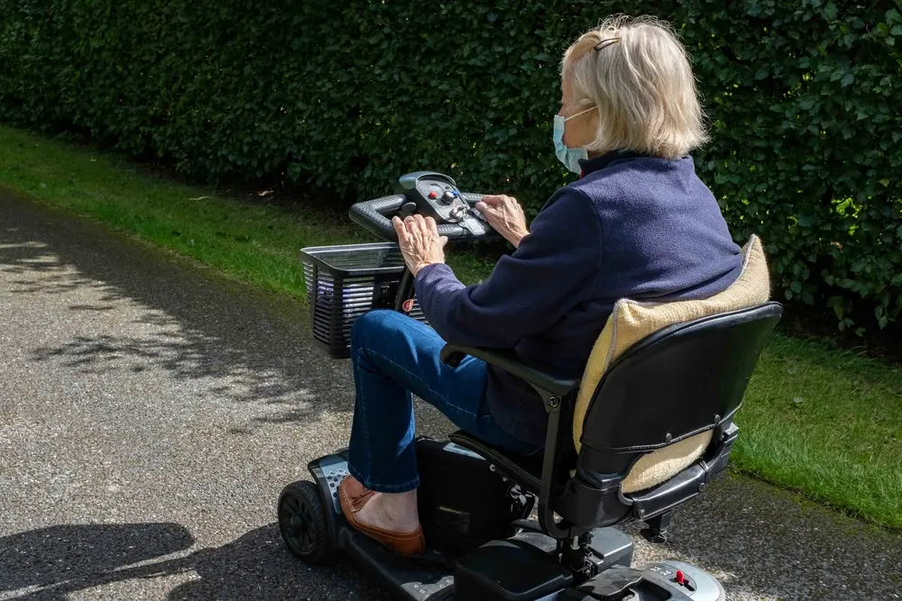 An elderly lady in a blue coat in a scooter