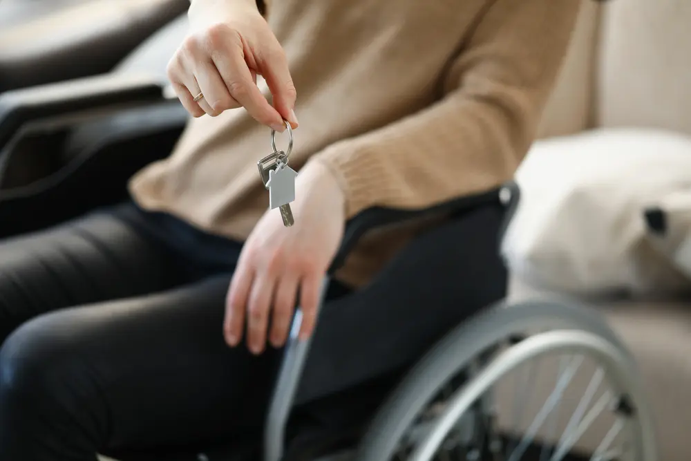 Woman in wheelchair holds keys to apartment