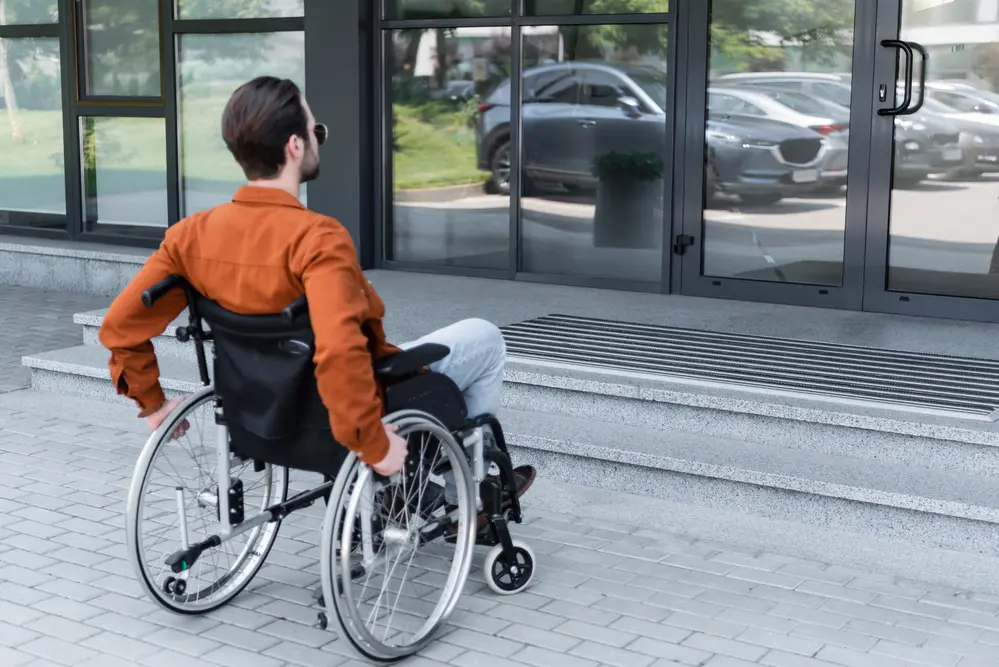 Young disabled man in wheelchair near entrance of a building
