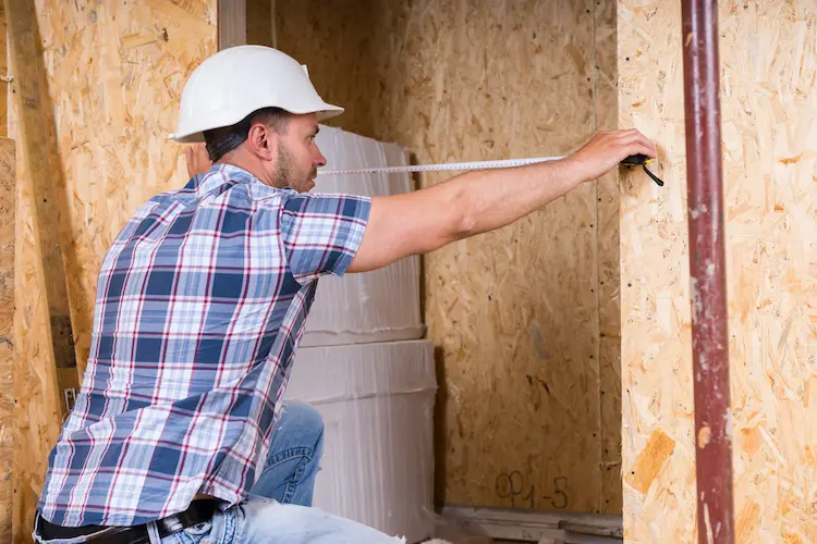 Construction Worker Measuring Width of Door Frame