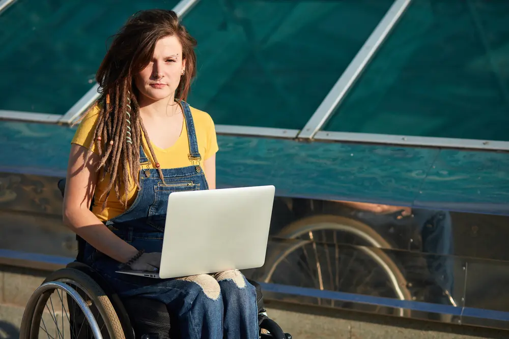 Young hipster girl with laptop looking at the camera