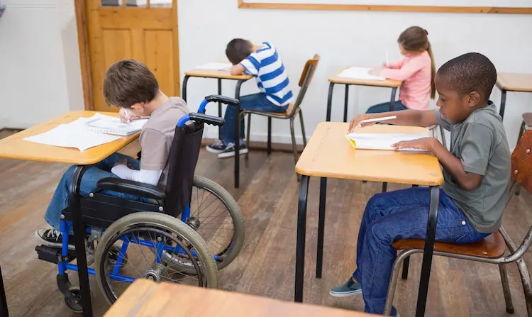 Disabled pupil writing in classroom