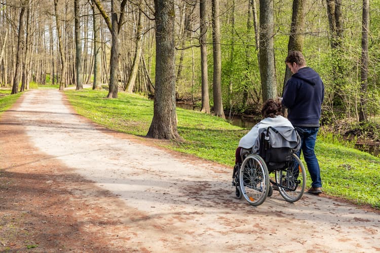 View from back to a woman in wheelchair at a park